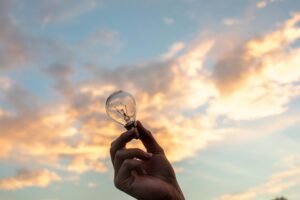 pexels-photo-1314410-1314410 A hand holds a light bulb against a scenic sunset sky, symbolizing creativity and innovation.
