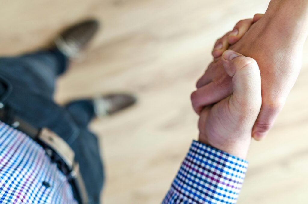 pexels-photo-928199-928199 Close-up of a handshake between two people inside an office, symbolizing trust and cooperation.